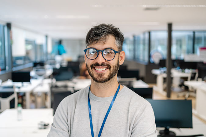 Happy IT Support technician in a large office wearing a lanyard.